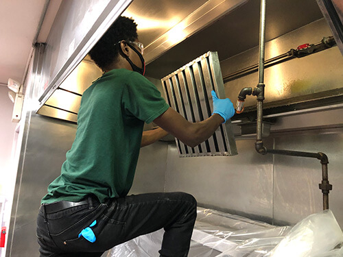 Service Technician cleaning an exhaust system