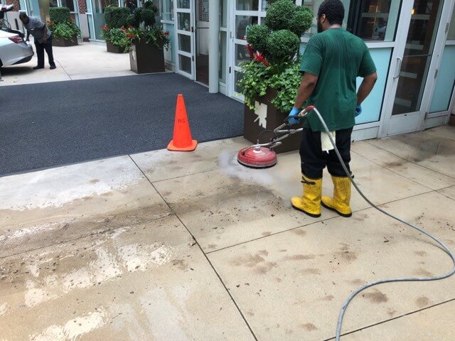 A CKC technician cleans a sidewalk
