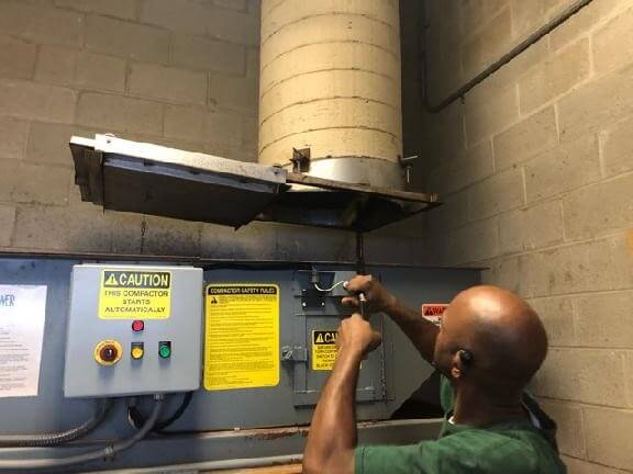 CKC technician cleaning bottom of a trash chute